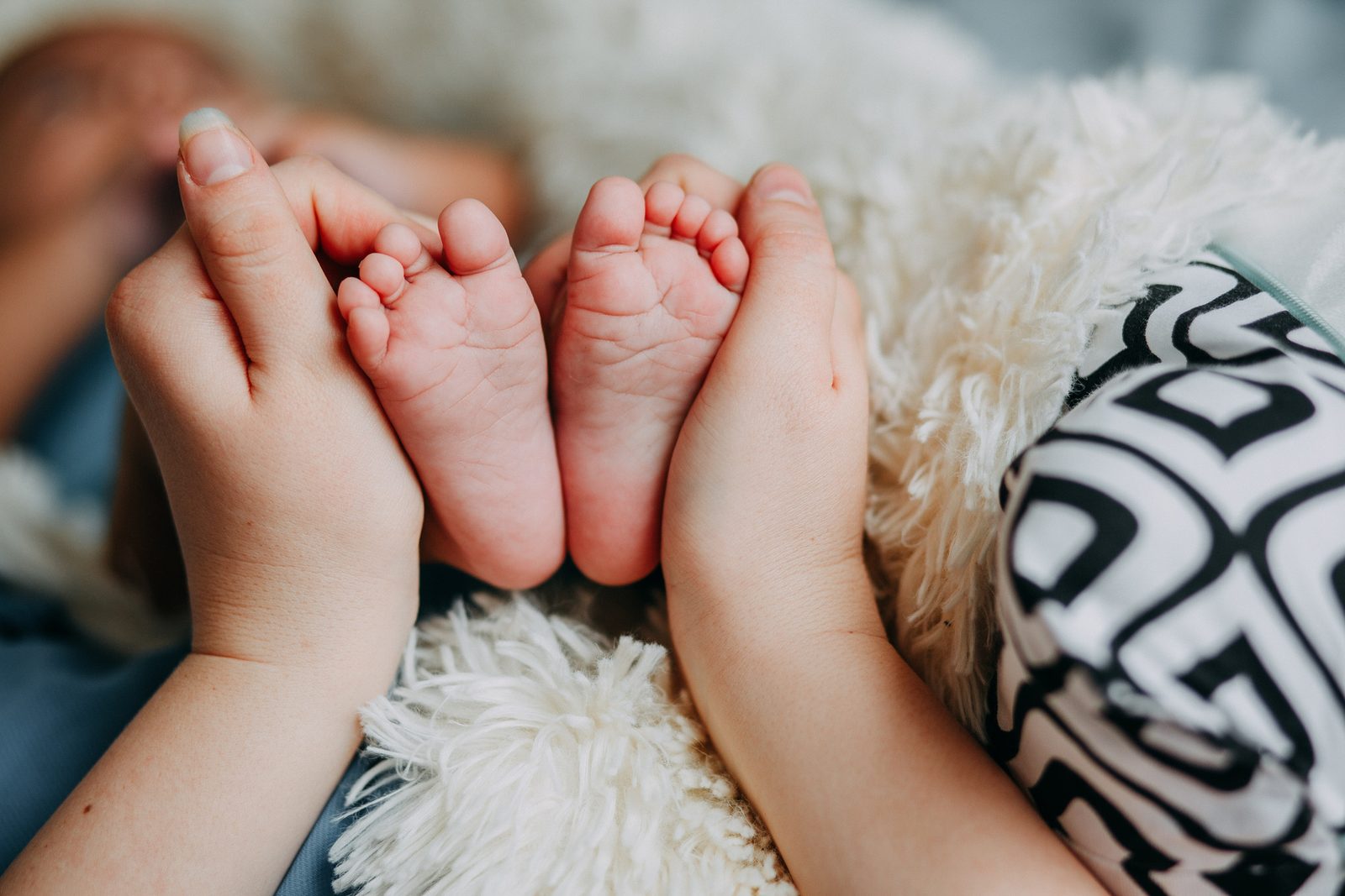 Newborn baby feet held gently