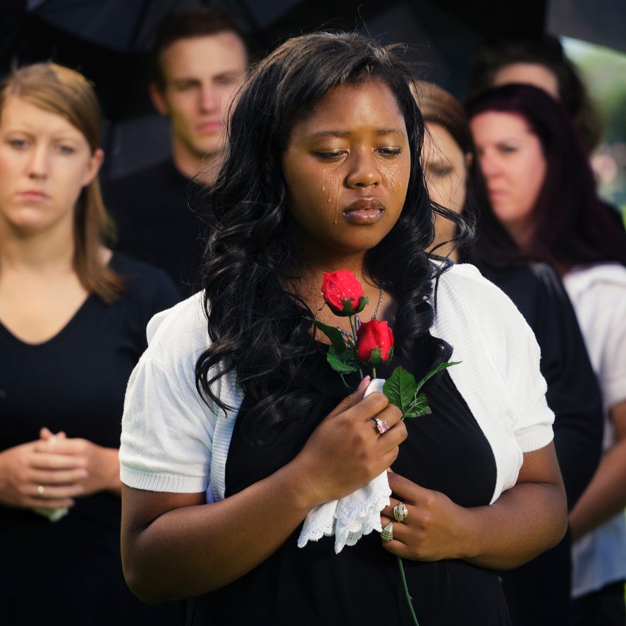 Person holding a single rose in remembrance